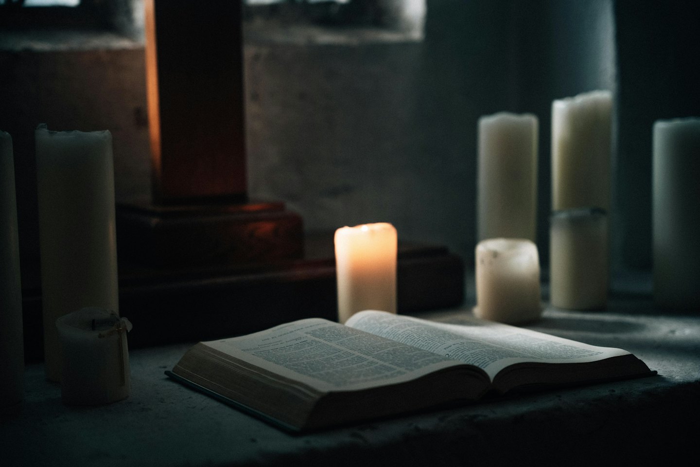Libro aperto su pietra con candela accesa.