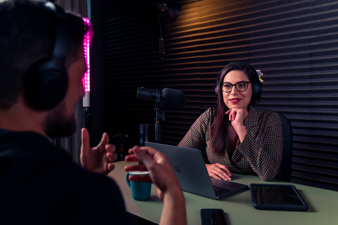 Due persone registrano un podcast in uno studio con microfoni.